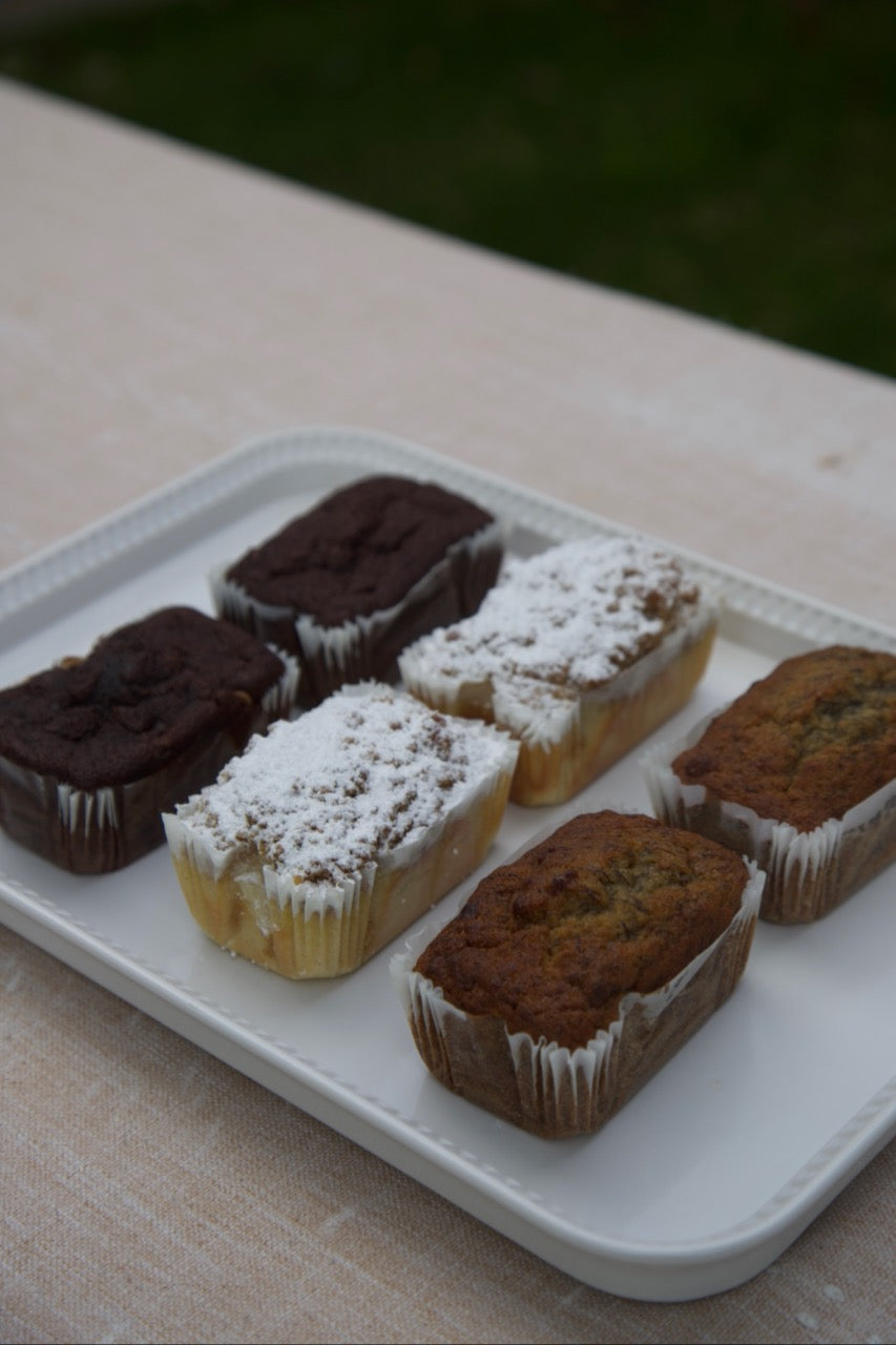 Sourdough banana bread, chocolate zucchini bread, coffee cake, and pumpkin spice loaf made with organic premium ingredients on an elegant white tray